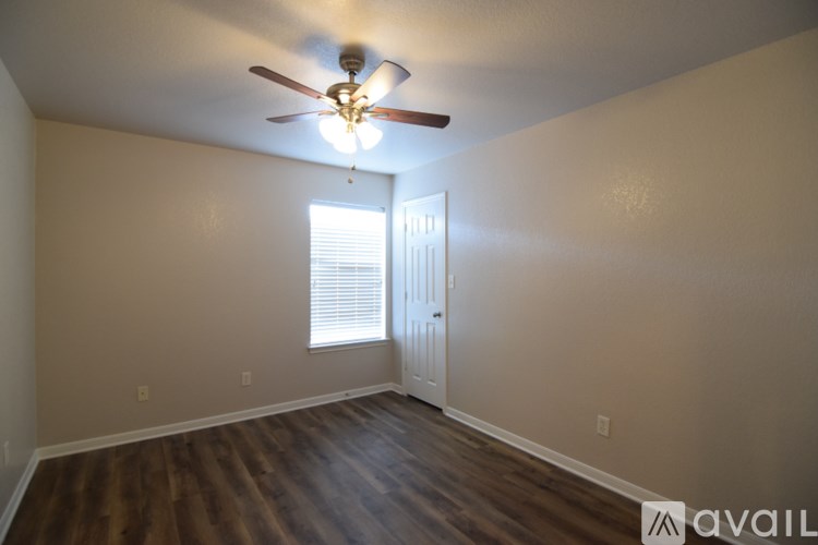 A room with a ceiling fan and wooden flooring.