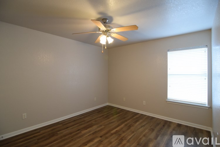 A room with a ceiling fan and wooden flooring.