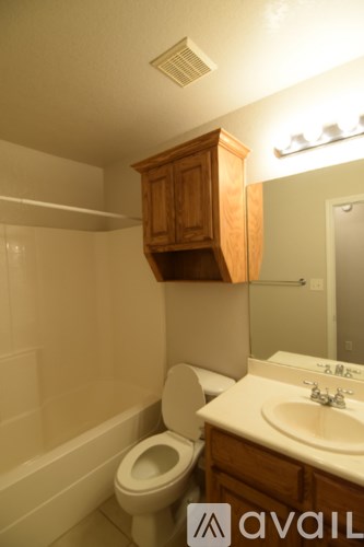 A bathroom with a toilet, sink and mirror.