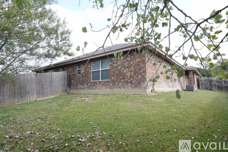 A house with a brown brick exterior and a white window is surrounded by a wooden fence.