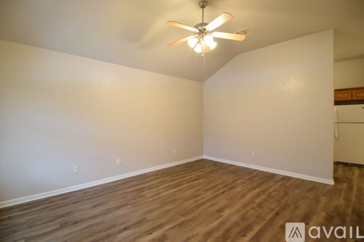 A room with a ceiling fan and wooden flooring.
