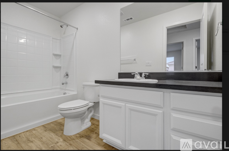 A white toilet is in a bathroom with a black counter.