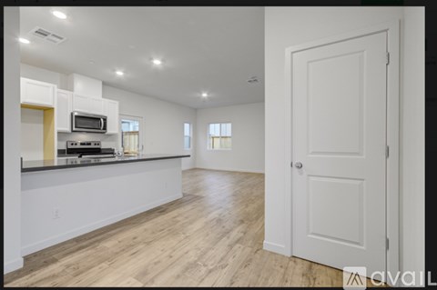 A spacious kitchen with white cabinets and a wooden floor.