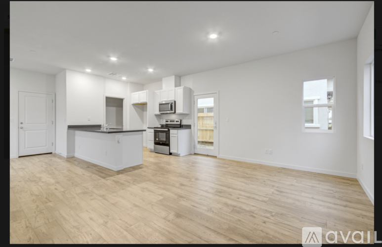 A spacious kitchen with wooden flooring and white walls.