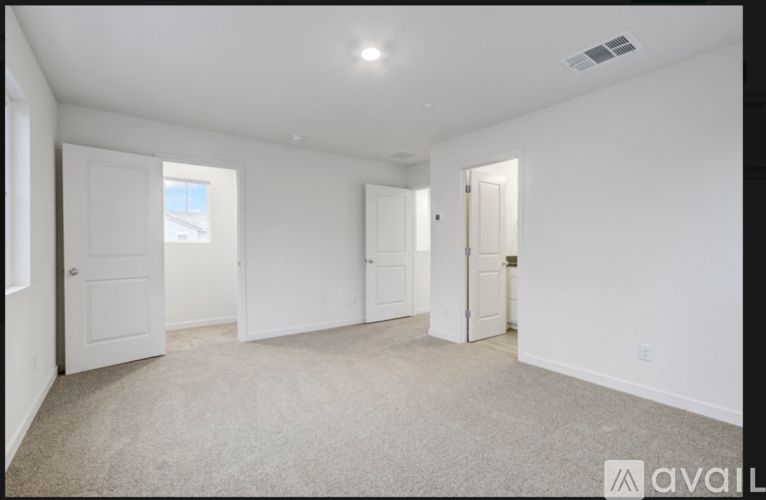 A spacious room with white walls and carpeted floor.