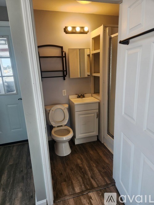 A bathroom with a toilet, sink, and mirror.