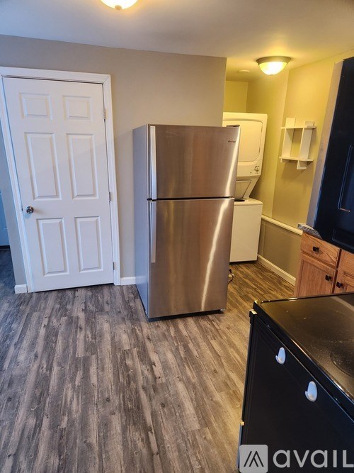 A kitchen with a stainless steel refrigerator and wooden flooring.