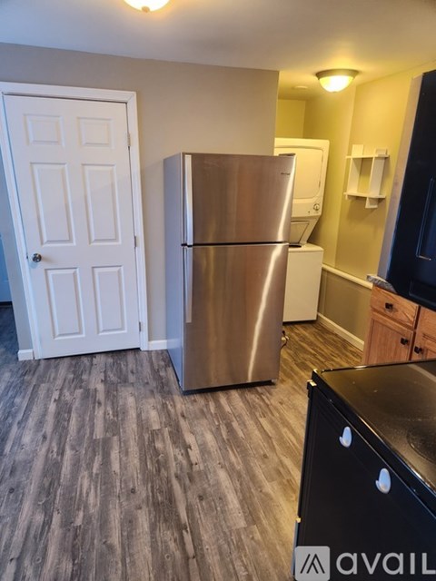 A kitchen with a stainless steel refrigerator and wooden flooring.