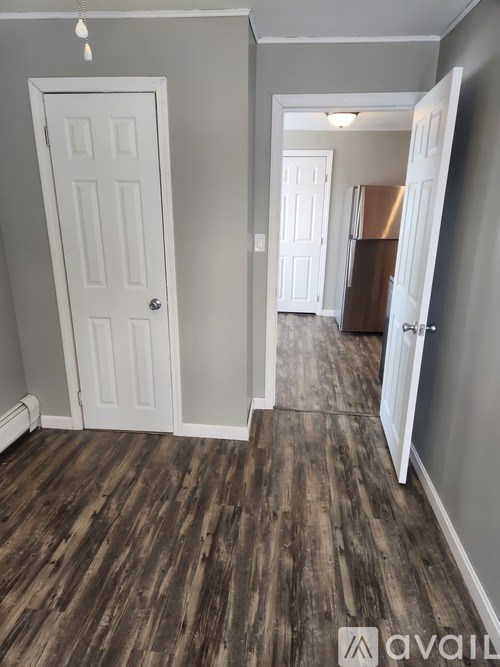 A hallway with a white door and a wooden floor.