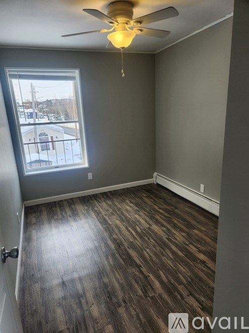 A room with a ceiling fan and a window overlooking a street.
