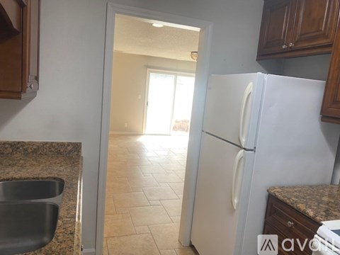 A kitchen with a white refrigerator and a sink.