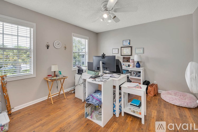 A room with a desk, chair, and a fan.