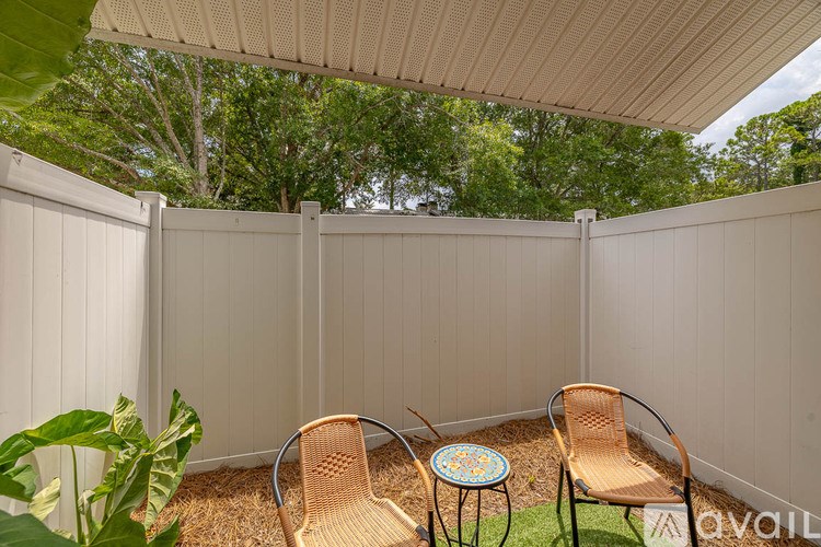 A patio with a white fence and two chairs.