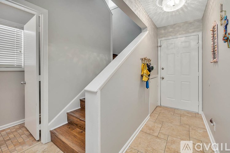 A room with a door, a window with blinds, and a wall with a light switch.