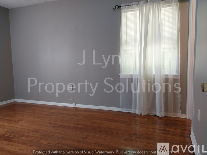 A room with wooden floors and a window with white curtains.