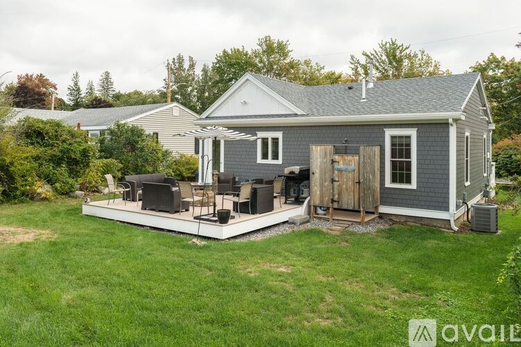 A house with a grey roof and a grey and white house with a deck in front.