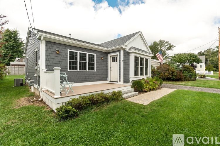 A small house with a grey roof and white trim is for sale.