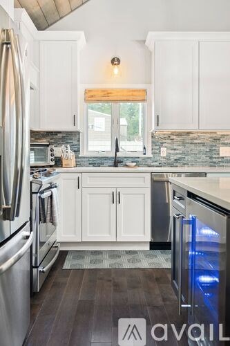 A kitchen with white cabinets and a wooden window.