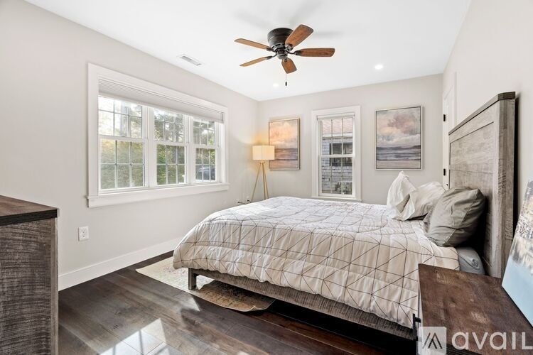 A bedroom with a bed, a ceiling fan, and pictures on the wall.