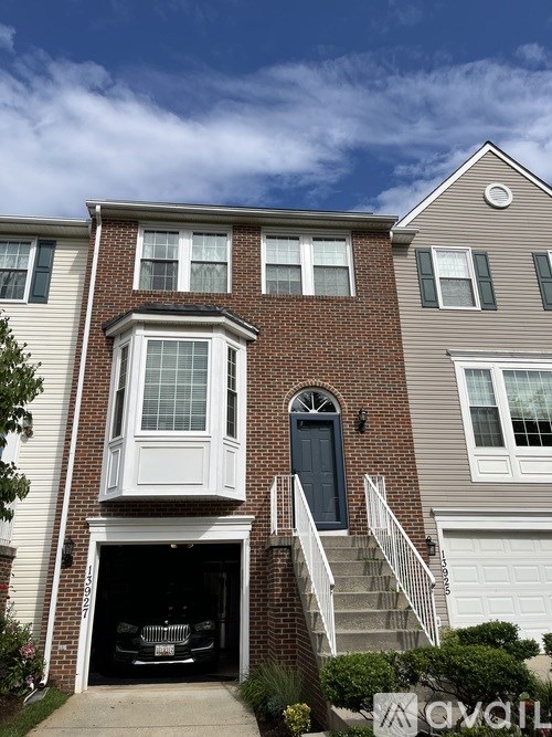 A two-story house with a garage and a car parked inside.