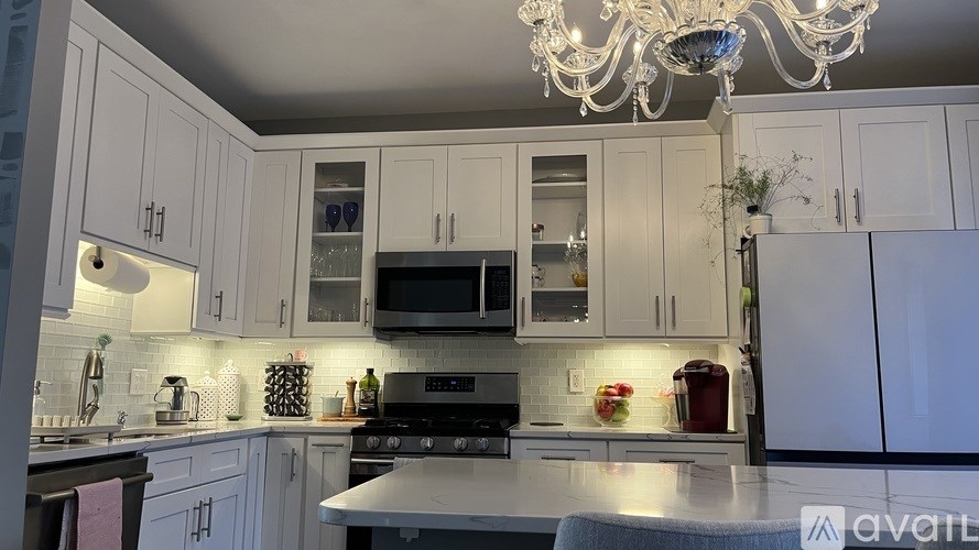 A kitchen with white cabinets and a chandelier.