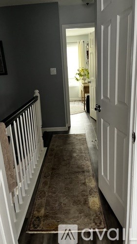 A hallway with a carpeted floor and a white door.
