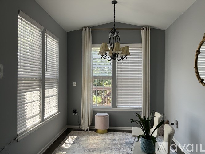 A room with a window, curtains, and a chandelier.