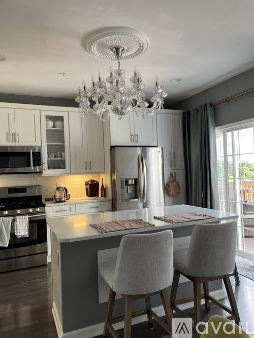 A kitchen with a white chandelier and grey cabinets.