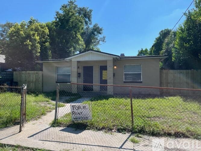 A house is for rent with a fence surrounding it.