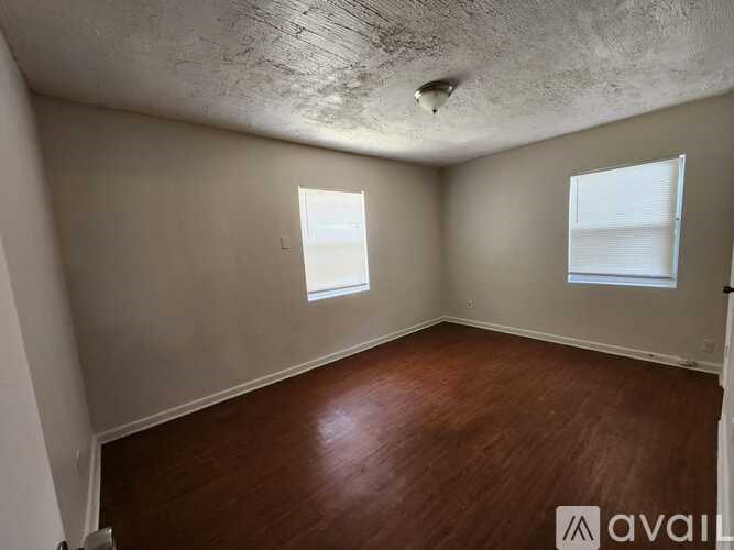 A room with wooden floors and two windows.