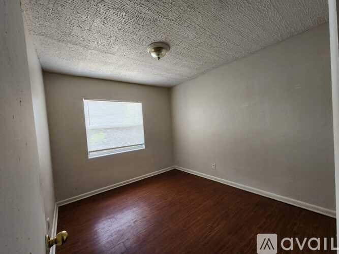 A room with a window and wooden flooring.