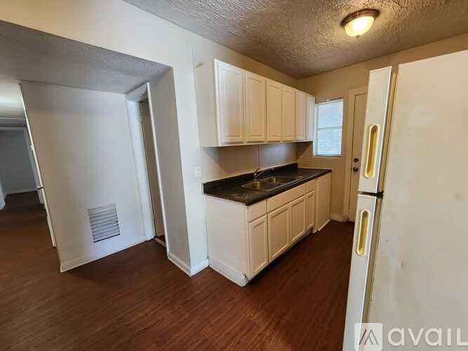 A kitchen with white cabinets and a black countertop.