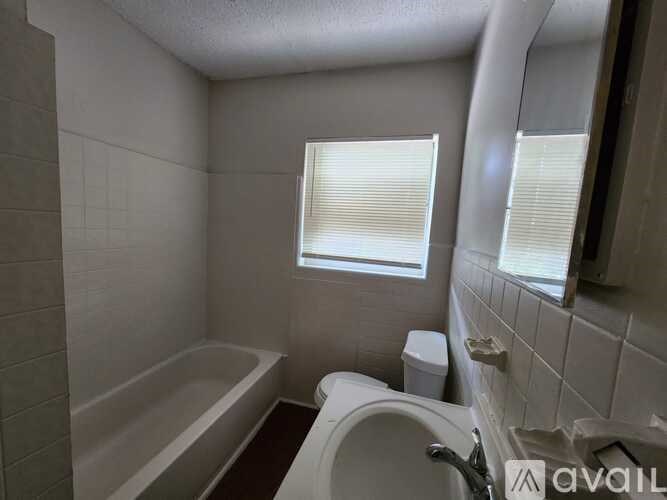 A bathroom with a tub, toilet, and sink.