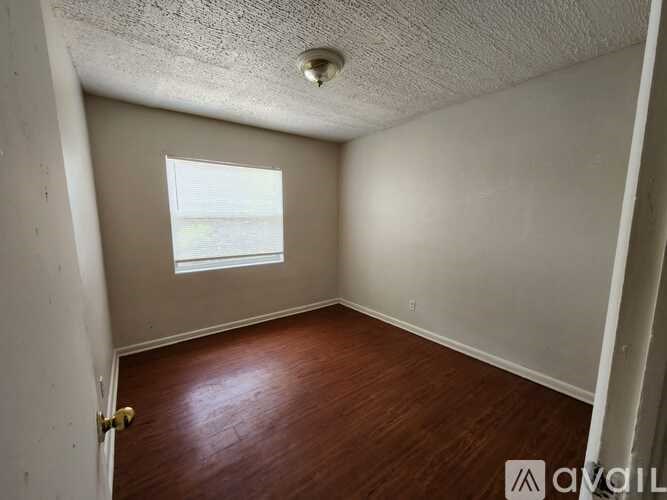 Empty room with a window and wooden floor.