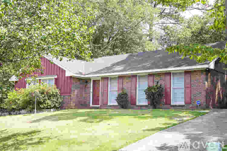 A red brick house with a green lawn in front.