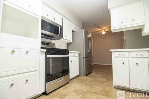 A kitchen with white cabinets and appliances.