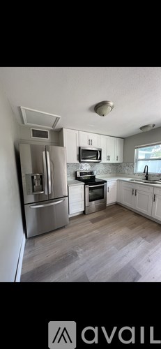 A kitchen with a refrigerator, microwave, oven, and cabinets.