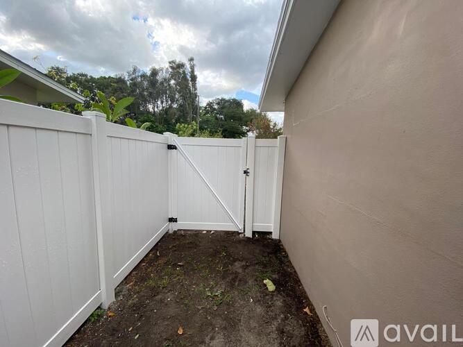 A white fence with a gate is in front of a house.