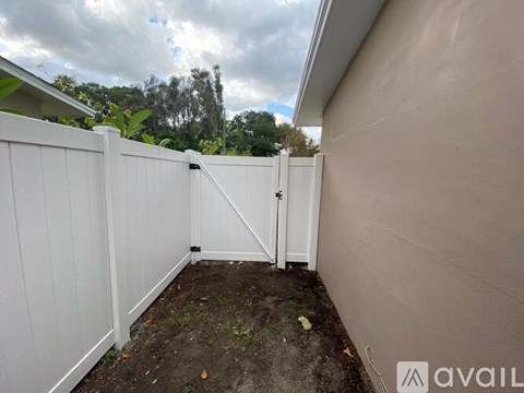 A white fence with a gate is in front of a house.