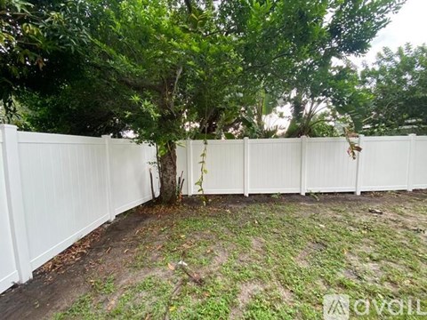A white fence encloses a yard with a tree in the middle.