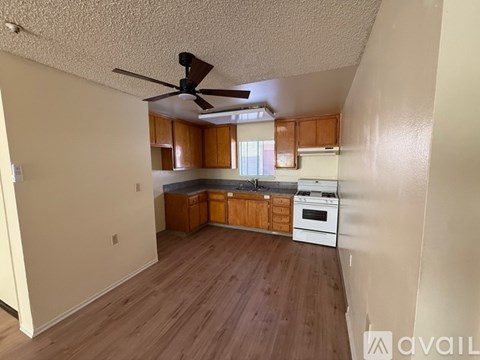 A kitchen with wooden floors and a ceiling fan.