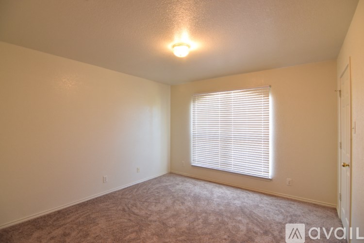 A room with a carpeted floor and a window with blinds.