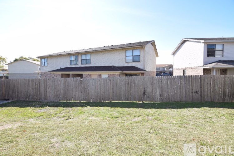 A wooden fence separates two houses.