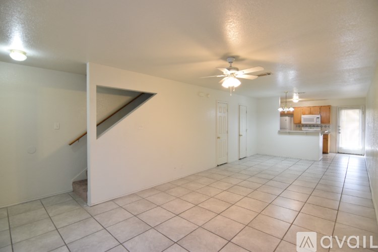 A spacious room with a fan and a staircase.