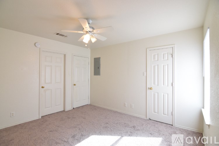A room with a carpeted floor and a ceiling fan.