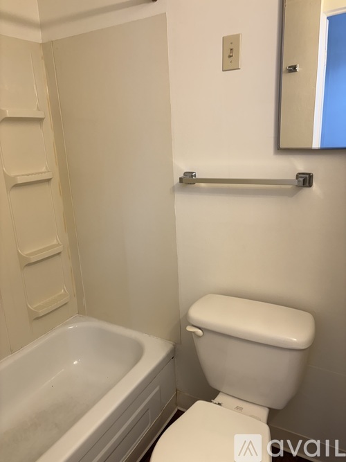 A white toilet in a bathroom with a bathtub and a mirror.
