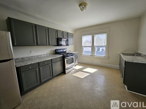 A kitchen with black cabinets and a white refrigerator.