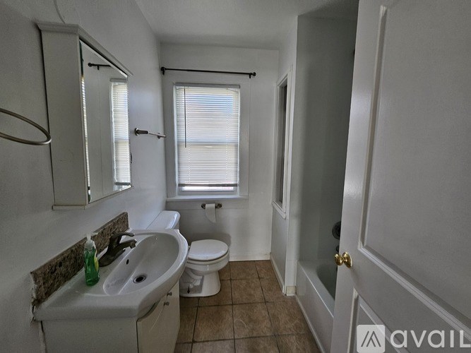 A bathroom with a toilet, sink, and window.