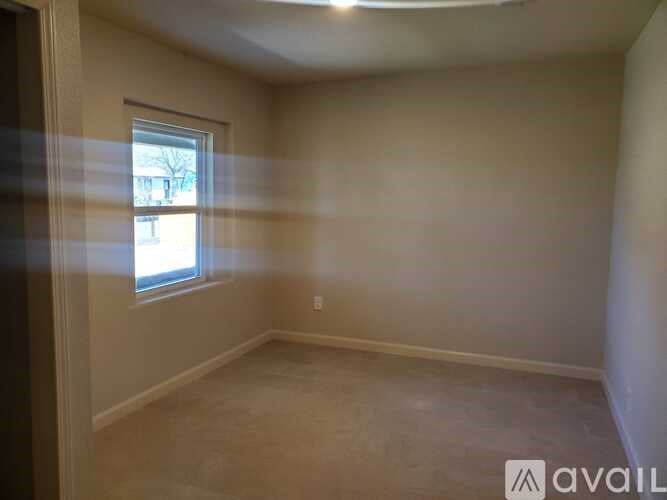 A room with beige walls and a window with a view of a building outside.