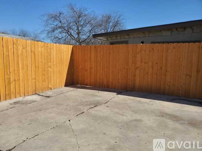 A backyard with a wooden fence and a concrete ground.